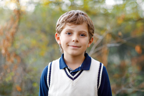 Portret chłopca cool kid w lesie. Szczęśliwy, zdrowe dziecko zabawy w ciepły słoneczny dzień wczesną jesienią. Rodzina, natura, miłość i aktywnego wypoczynku. Dziecko w szkolny mundurek. - Zdjęcie, obraz
