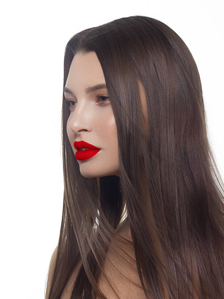 Close-up of beauty girl with long straight developing hair and radiant daytime makeup on her face. Skin care natural cosmetic in the spa salon or cosmetology. Red lipstick on the lips of a young woman - Foto, afbeelding