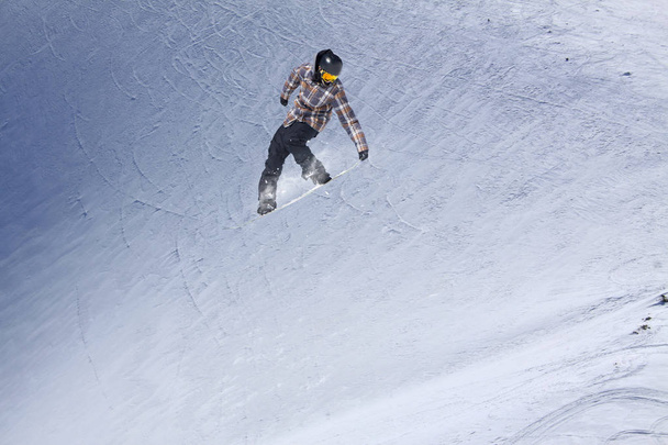 Snowboarder flying on the background of snowy slope. Extreme winter sports, snowboarding. - Foto, Imagen