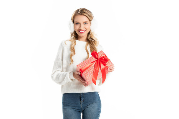 uśmiechający się, piękna, młoda kobieta w strój zima trzyma prezent na białym tle - Zdjęcie, obraz