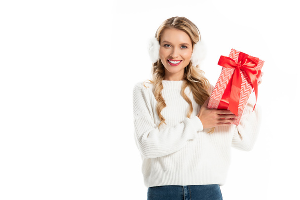 красивая улыбающаяся девушка в зимнем наряде с подарочной коробкой, изолированной на белом
 - Фото, изображение