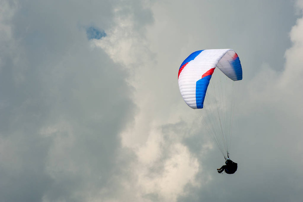 Yalnız yamaçparaşütü bulutlar arka planı mavi gökyüzünde uçan. Güneşli bir havada yamaç paraşütü. - Fotoğraf, Görsel
