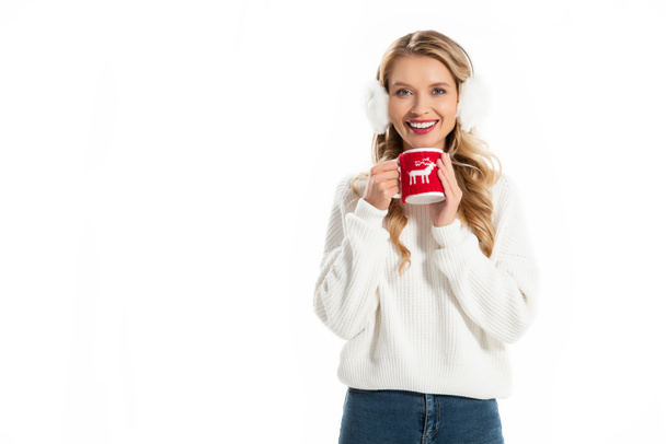 smiling woman in winter earmuffs holding cup with hot drink isolated on white - Photo, Image