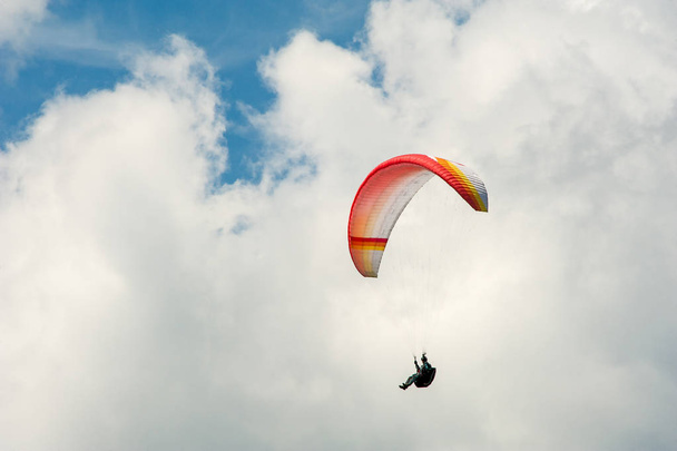 Alone paraglider flying in the blue sky against the background of clouds. Paragliding in the sky on a sunny day. - Photo, Image