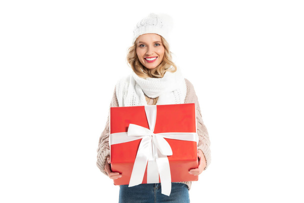 mosolygó lány téli ruhában gazdaság nagy piros ajándék elszigetelt fehér - Fotó, kép