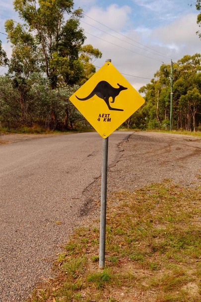 Viesti maalattu musta Kenguru ensi 4km sininen taivas ja Australian pensas taustalla. Matkalta löytyneet australialaiset opasteet - inspiraatiota seikkailuun, matkamuistoihin ja esitteeseen - Valokuva, kuva