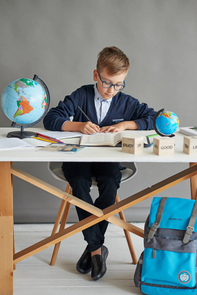 um menino com óculos fazendo uma lição na aula fazendo uma tarefa
 - Foto, Imagem