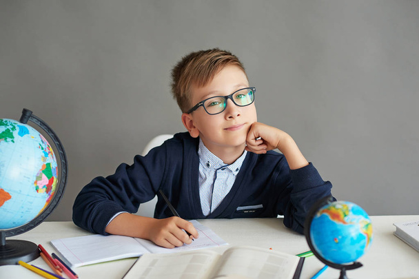 ένα αγόρι με γυαλιά κάνει ένα μάθημα στην τάξη κάνει μια ανάθεση - Φωτογραφία, εικόνα