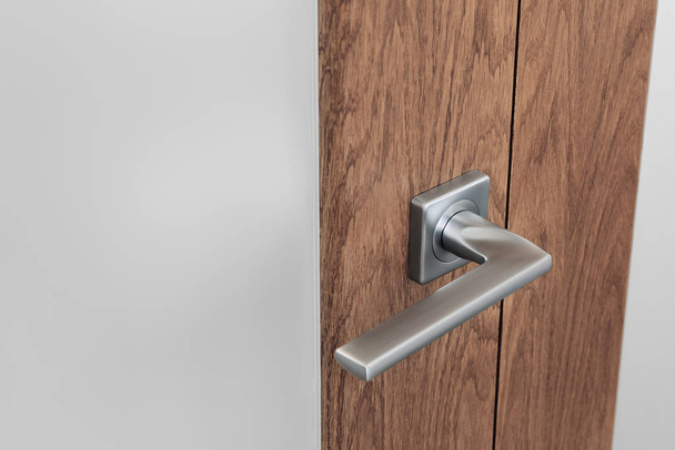 Close-up of modern steel door handle on interior door. Dark oak and frosted glas - Zdjęcie, obraz