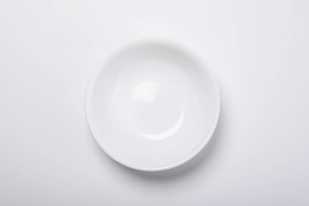 La mano de la mujer sostiene un plato aislado sobre fondo blanco.. - Foto, Imagen