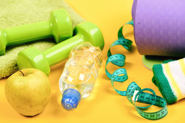 Dumbbells made of green plastic on yellow background - Foto, imagen