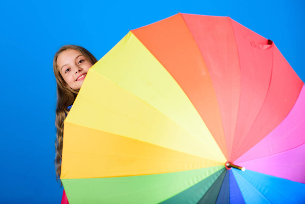 Kid peek out colorful rainbow umbrella. Color your life. Girl cheerful hide behind umbrella. Colorful umbrella accessory. Weather forecast concept. Stay positive though rainy day. Brighten up life - Zdjęcie, obraz