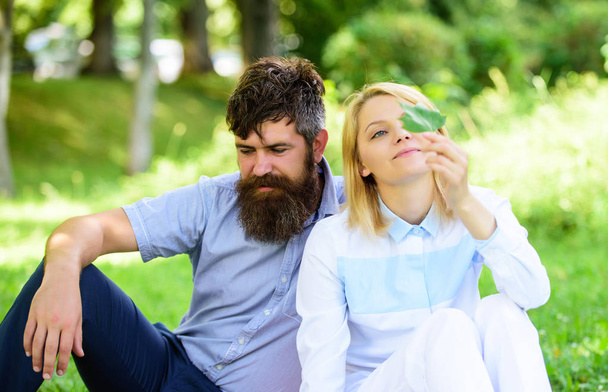 Couple bearded man and woman enjoy nature while sit on green grass meadow. Nature beauty concept. Woman enjoy relax nature background. Pure nature. Couple with green leaf relax natural environment - Photo, Image