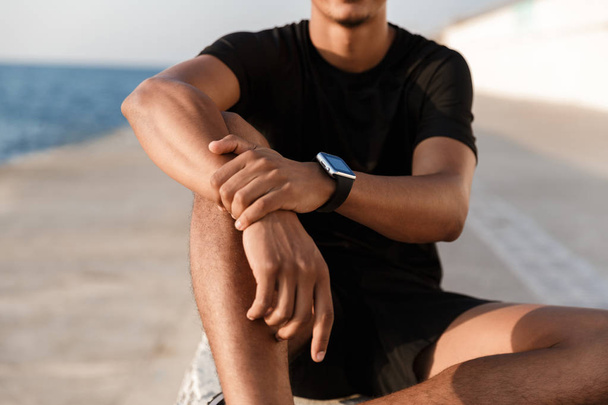 Cropped photo of handsome young guy sportsman sitting outdoors on the beach. - Fotografie, Obrázek