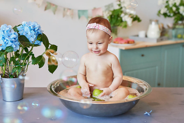 Παιδική υγιεινή. Σαμπουάν, περιποίηση μαλλιών και σαπούνι για παιδιά. Το παιδί κάνει μπάνιο σε μεγάλη μπανιέρα. Πλύσιμο, υγιεινή βρεφών, υγεία και περιποίηση δέρματος. Μωρό στο μπάνιο.  - Φωτογραφία, εικόνα