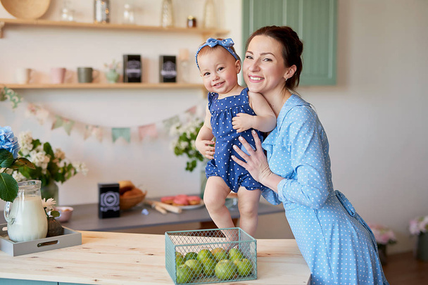 Mother's day greeting card. Family mother and baby daughter in morning have breakfast in kitchen. Spring card for Women's Day March 8. Happy family at home in kitchen. Family festive breakfast.  - Photo, Image