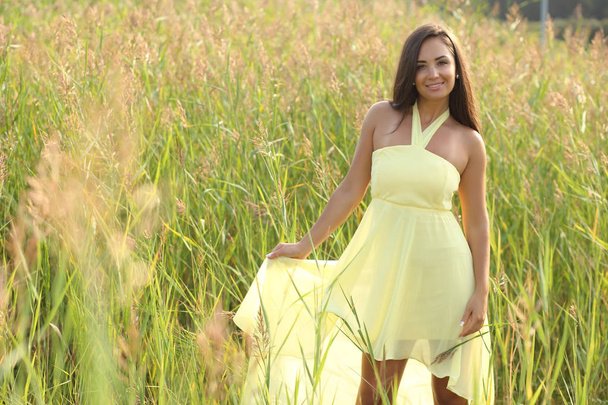 Молодая девушка в жёлтом платье, позирующая на природе
 - Фото, изображение