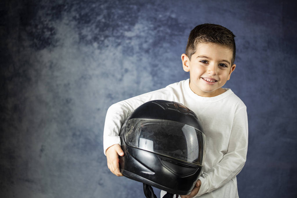 Little kid playing with a motorcycle helmet - Foto, Imagen
