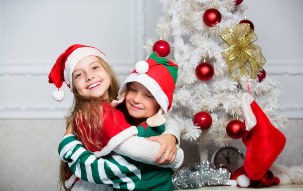 Frohe Weihnachten. Familientraditionen. Kinder feiern fröhlich Weihnachten. Kinder Weihnachtskostüme Weihnachtsmann und Elfe. Wintermaskerade-Konzept. Geschwister feiern Weihnachten oder treffen sich zu Neujahr - Foto, Bild