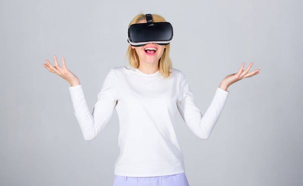 Woman using virtual reality headset. Young woman using a virtual reality headset with conceptual network lines. Portrait of an amazed girl using a virtual reality headset isolated on grey background. - Foto, Bild