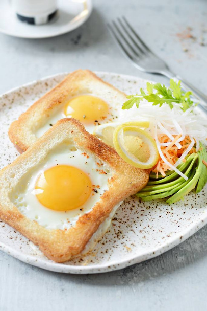 Американский завтрак на тарелке с жареными яйцами в тосте, с помидорами, свежим дайконом, морковью, рукколой и эспрессо. Жареное яйцо для традиционного завтрака
 - Фото, изображение