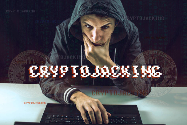 Um hacker com um rosto está tentando roubar criptomoeda usando um computador. Golpe em Cryptojacking
 - Foto, Imagem
