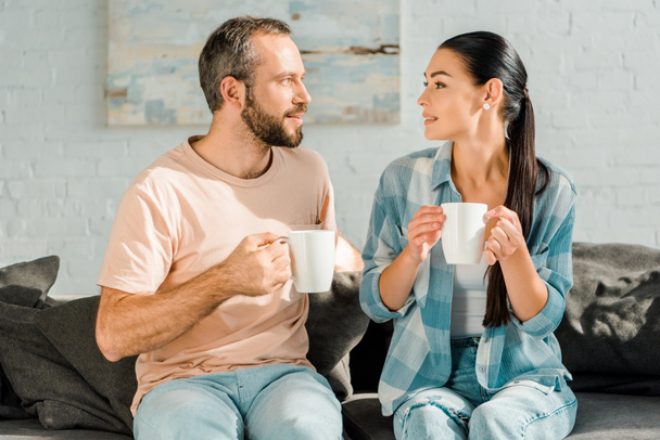 marito e moglie seduti sul divano, bevendo caffè e guardandosi l'un l'altro
 - Foto, immagini