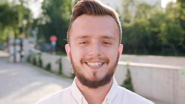A fiatalember visel egy fehér inget mosolyogva a városban - Felvétel, videó