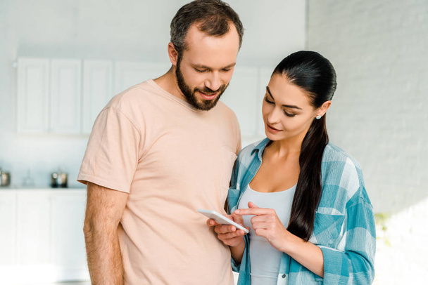 beautiful couple in casual clothes using smartphone at home - Photo, Image