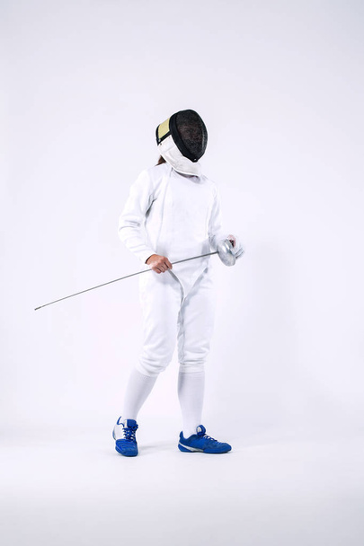 Fencer athlete wearing mask and white fencing costume and holding the sword, . Isolated on white background - Photo, image