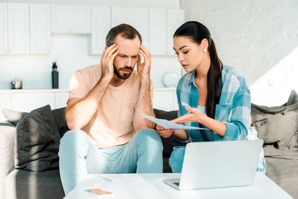 stressed couple sitting on couch, using laptop and having financial problems - Photo, Image