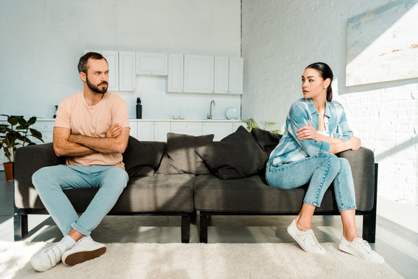 frustrated couple having argument and sitting at opposite ends of sofa - Foto, imagen