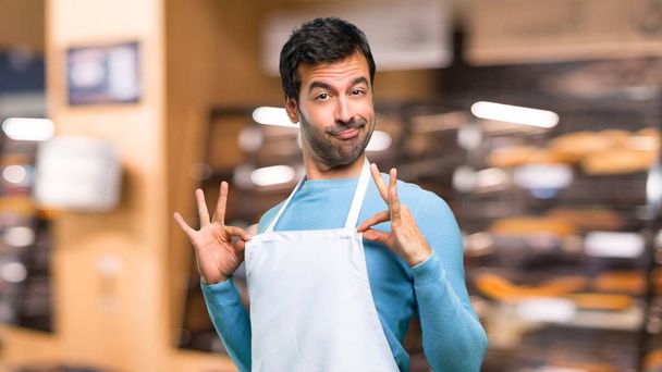 Hombre usando un delantal orgulloso y auto-satisfecho en el amor mismo concepto en una panadería
 - Foto, imagen