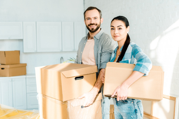husband and wife carrying cardboard boxes and packing for new house, moving concept - Photo, Image