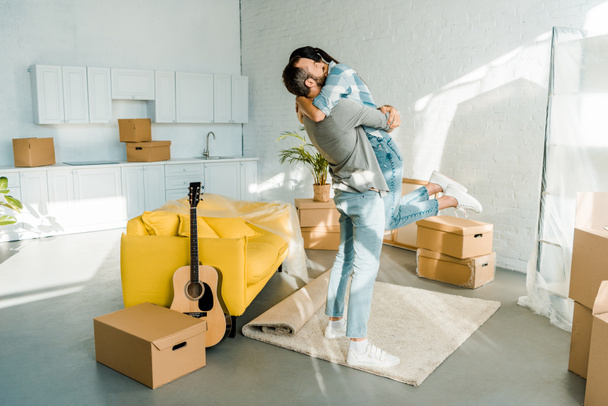 mari heureux étreignant femme lors de l'emballage pour nouvelle maison, concept de déménagement
 - Photo, image