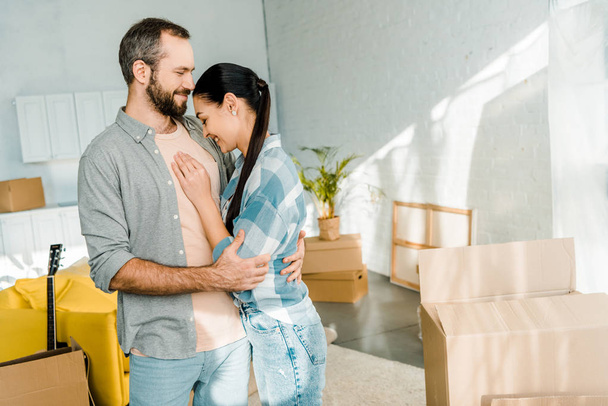 laughing couple embracing while packing for new house, moving concept - Zdjęcie, obraz