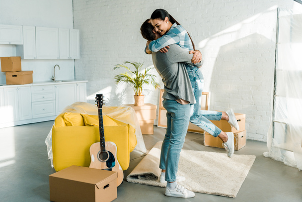 ευτυχισμένος σύζυγος αγκαλιάζει γυναίκα ενώ συσκευασίας για το νέο σπίτι, κινείται έννοια - Φωτογραφία, εικόνα