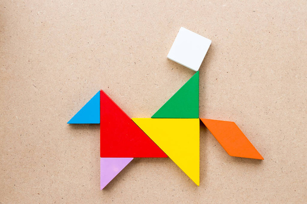 Puzzle couleur tangram en forme de cheval de promenade homme sur fond de bois
 - Photo, image