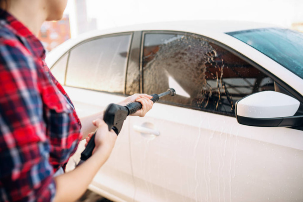 Pessoa feminina lavar a espuma do vidro do carro. Mulher em auto-serviço de lavagem de automóveis. Limpeza de veículos ao ar livre no dia de verão
 - Foto, Imagem
