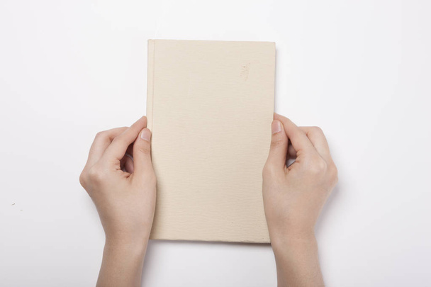 La mano femenina lleva un libro de marfil sobre la mesa blanca - Foto, Imagen