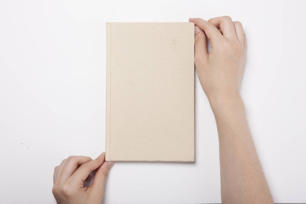 La mano della donna tiene un libro d'avorio sul tavolo bianco - Foto, immagini