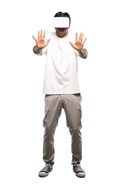A full-length shot of a Man using VR glassestrying to touch something on isolated white background - Fotó, kép
