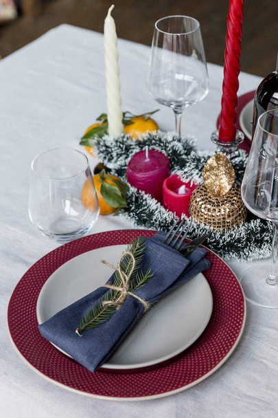 Christmas and new year's serving plate, gray plate on red plate, with fork and knife and blue napkin with Christmas tree branch at white table - Fotografie, Obrázek