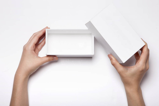 La mano de mujer tiene una caja blanca en la mesa blanca - Foto, Imagen