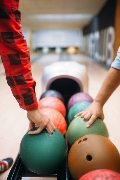 Two male bowlers takes balls from feeder. Bowling alley players prepares to makes a throw. Classical tenpin game in club, active leisure - Foto, immagini
