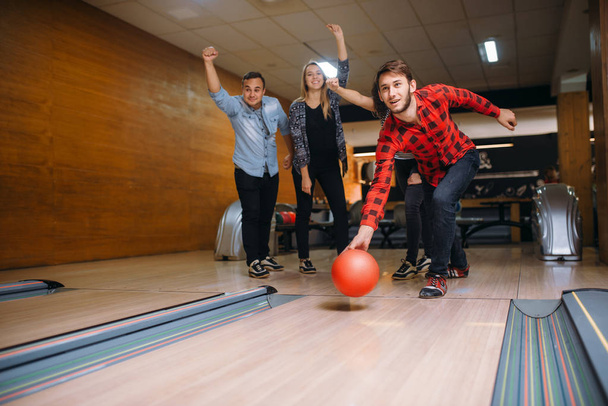 Male bowler throws ball on lane, strike shot. Bowling alley teams playing the game in club, active leisure - Foto, Imagem