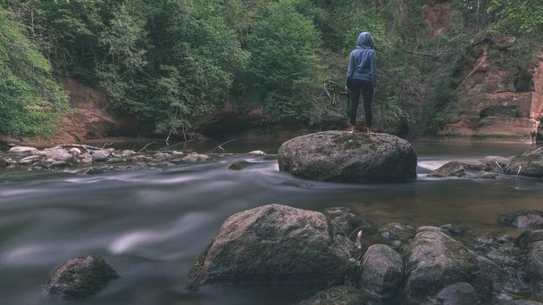person in blue hoodie standing on rock with long exposure rocky mountain river - Fotoğraf, Görsel