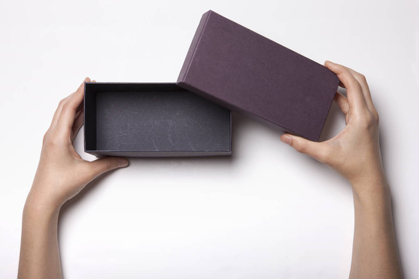 Женская рука держит черный ящик на белом столе - Фото, изображение