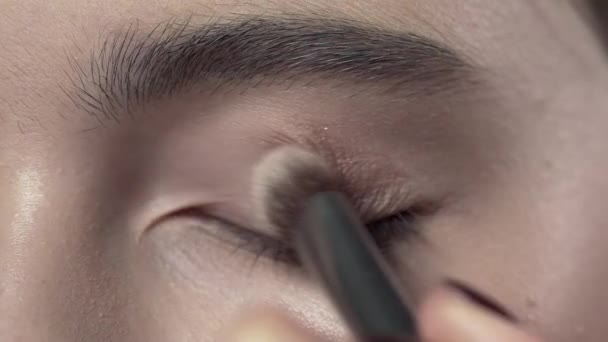 Macro shot of applying makeup to the womans eyelid, evening makeup, smokey eyes, makeup in progress, close up makeup - Footage, Video