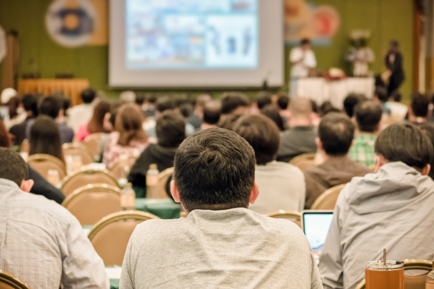 Вид ззаду Аудиторія слухачі представляють слайд на сцені в конференц-залі або семінарі зустрічі, бізнес та освітня концепція
 - Фото, зображення